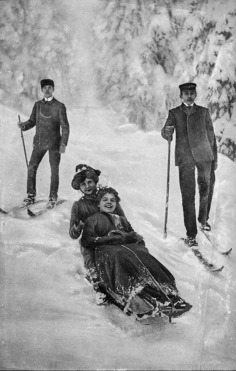 To damer på kjelke, to menn på ski
