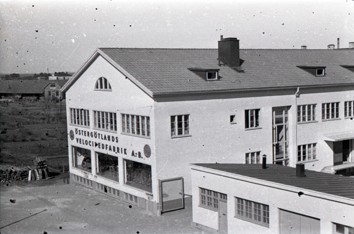 Östergötlands  Velocipedfabrik på Sturegatan, fotograferad från Klostergatan. I bakgrunden syns kolonilotterna på Bantorget, där i dag det s. k. Volvohuset ligger.