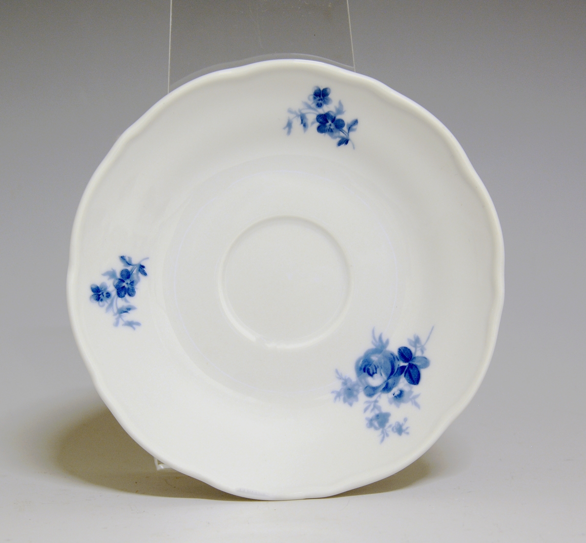 Kaffeskål av porselen. Hvit glasur. Blå rose på fanen.
Modell: Victoria, 1800
Dekor: Blå rose.
