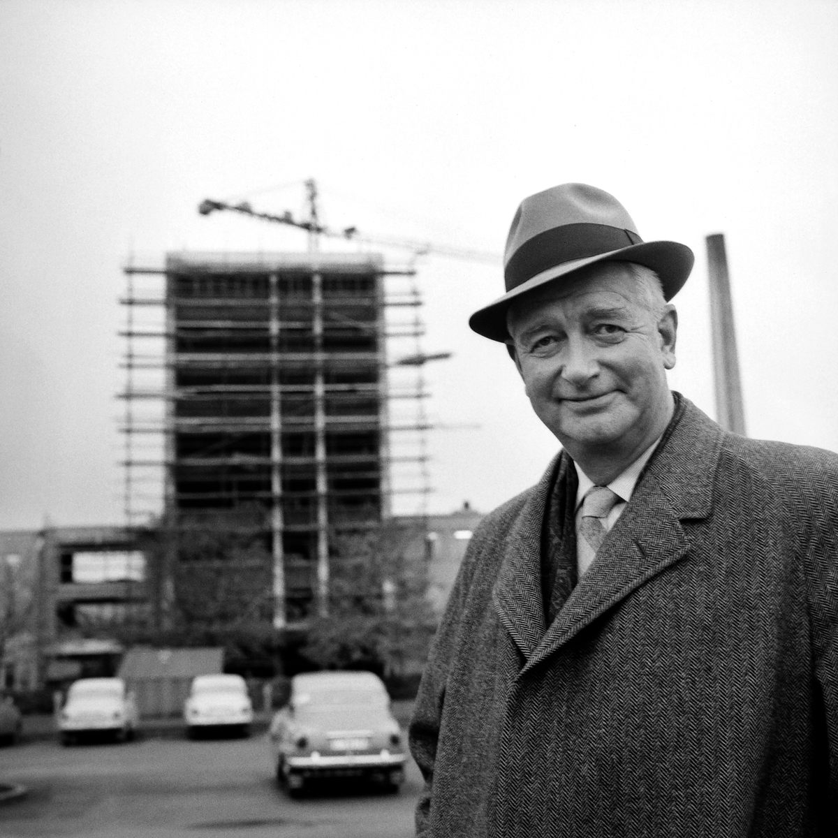 Tryggve Holm, verkställande direktör för SAAB, Svenska Aeroplan Aktiebolaget åren 1950–1967. Här posträtterad 1962. I bakgrunden pågår byggnation i företagets område.