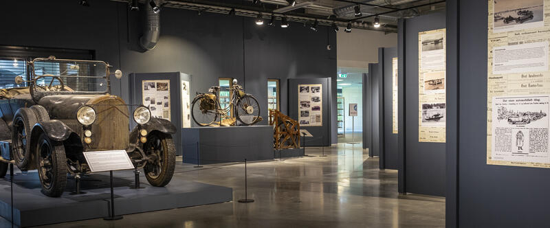 Fra utstillingen "Med kjørefrakk og lærstøvler" på Norsk kjøretøyhistorisk museum, med en bil, motorsykkel og diverse tekstplansjer.