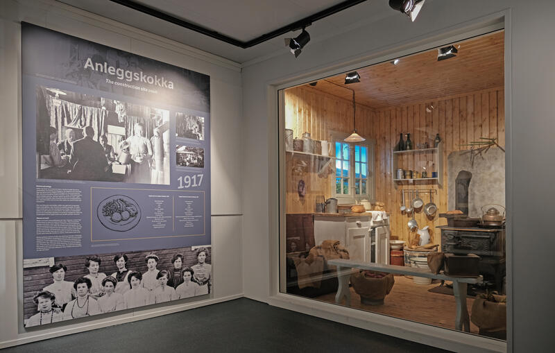 Hjørne fra utstilling om anleggskokka i Utstillingsbygget, Norsk fjellsprengningsmuseum. En tekstplansje og et tablå fra et anleggskjøkken anno 1917.
