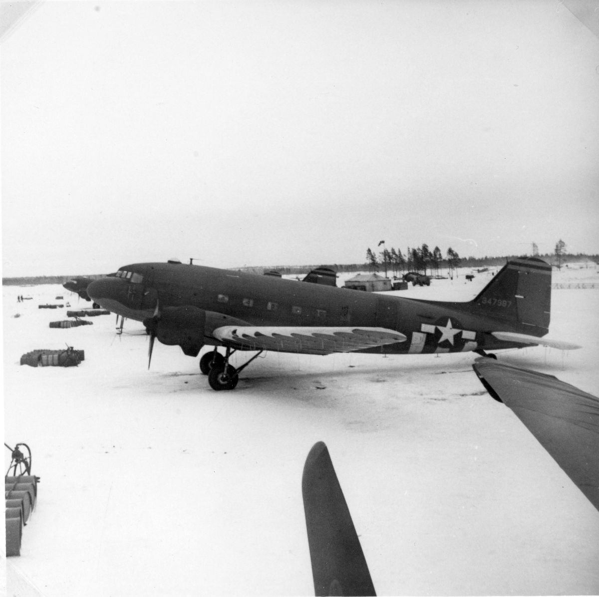 DC-47 transportfly oppstilt på flybasen på Kallax vinteren 1945. 12 fat med drivstoff og handpumper er plassert foran hvert fly.