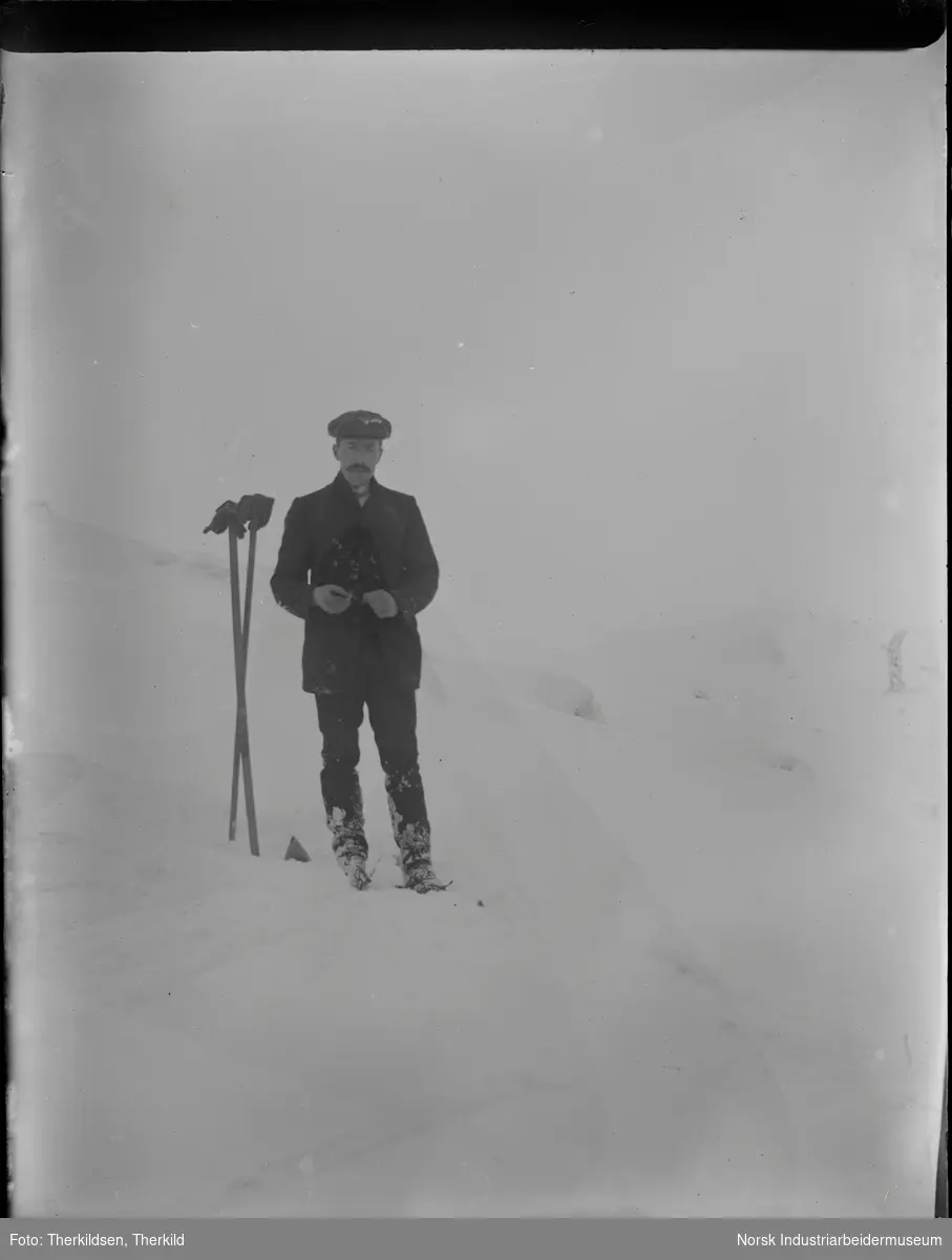 Mann på skitur. Stavene står samlet ved siden av i snøen.