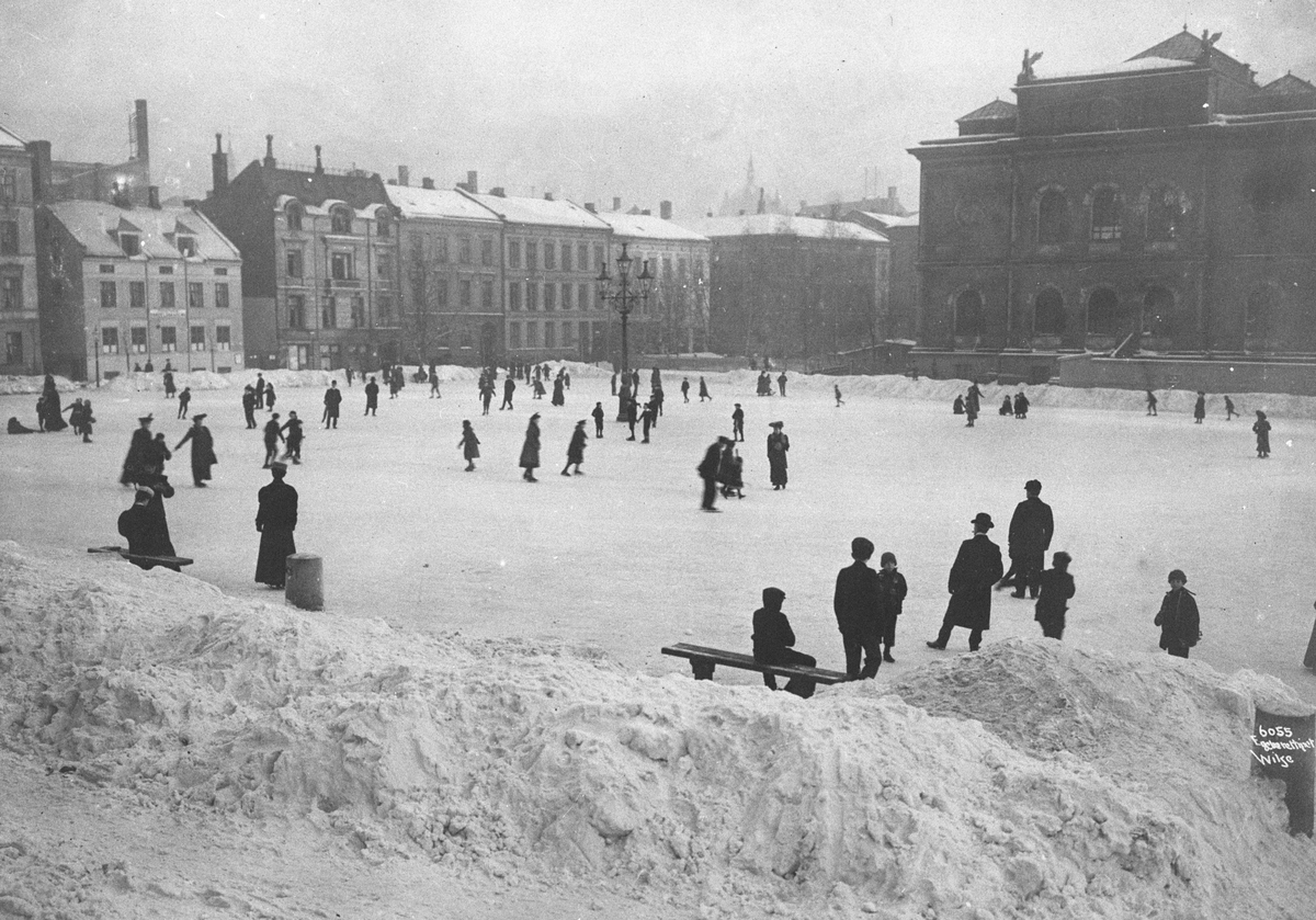 Folk i alle aldre går på skøyter på Tullinløkka skøytebane. Nasjonalgalleriet sees i bakgrunnen. Fotografert 1. desember 1907.