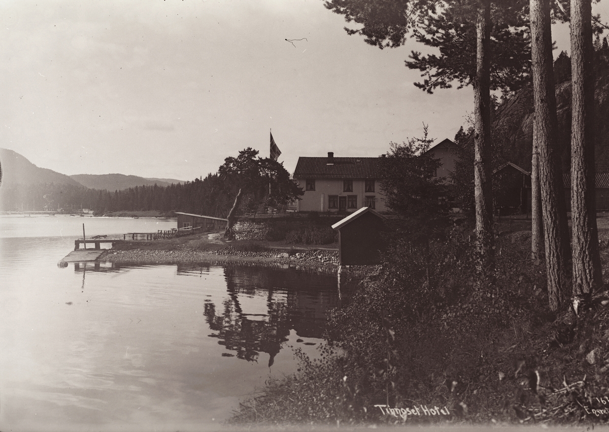 Utsikt langs bredden av Tinnsjå mot Tinnoset Hotel hvor flagget er heist til topps, 1914.