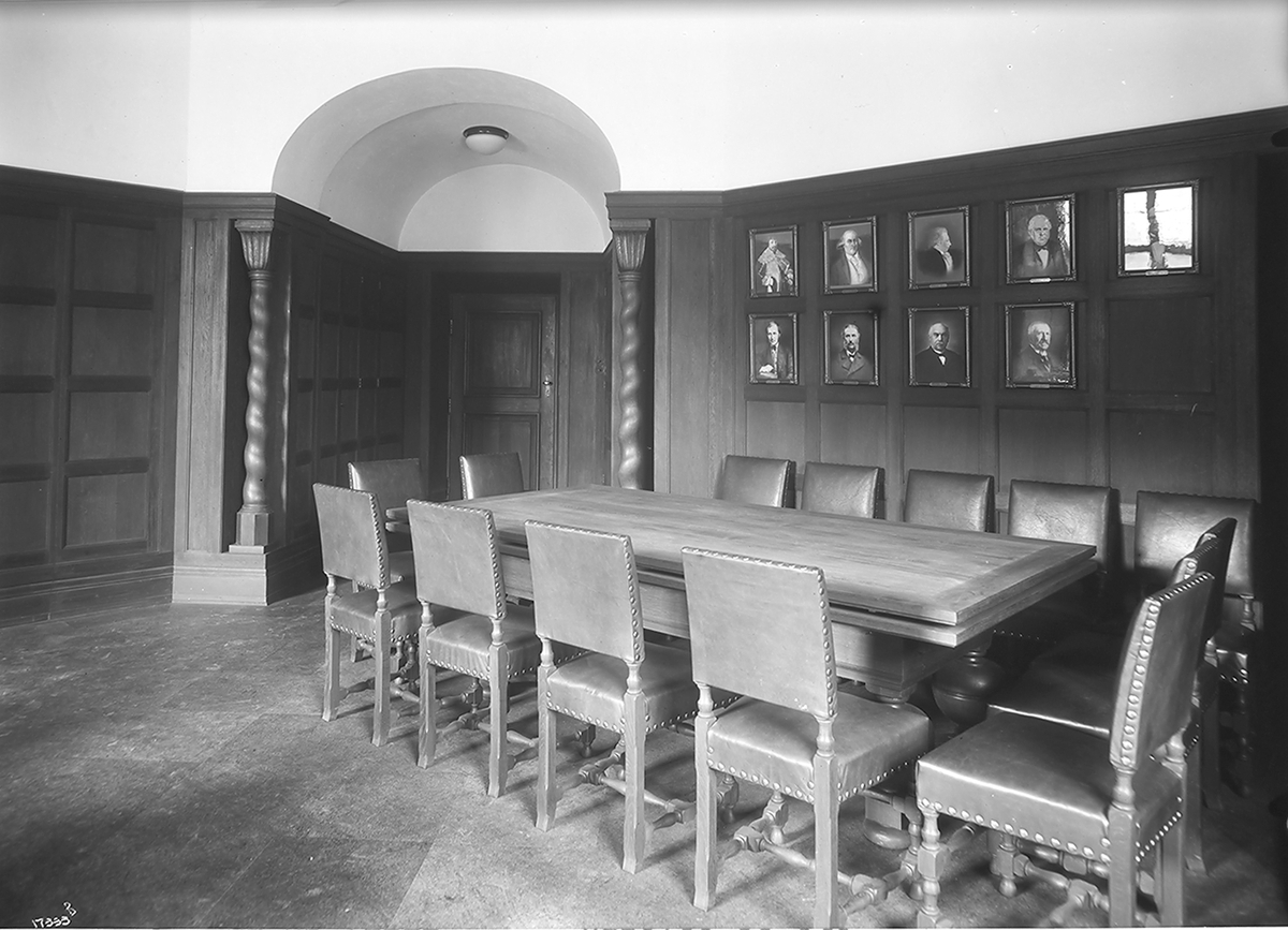 Bord med stoler rundt i et kontor, flere portretter henger på veggen, Oslo hovedpostkontor. Fotografert 1923.