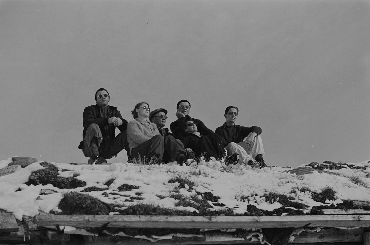 Seks personer soler seg på setertaket i påseken. Fotografert 1940.