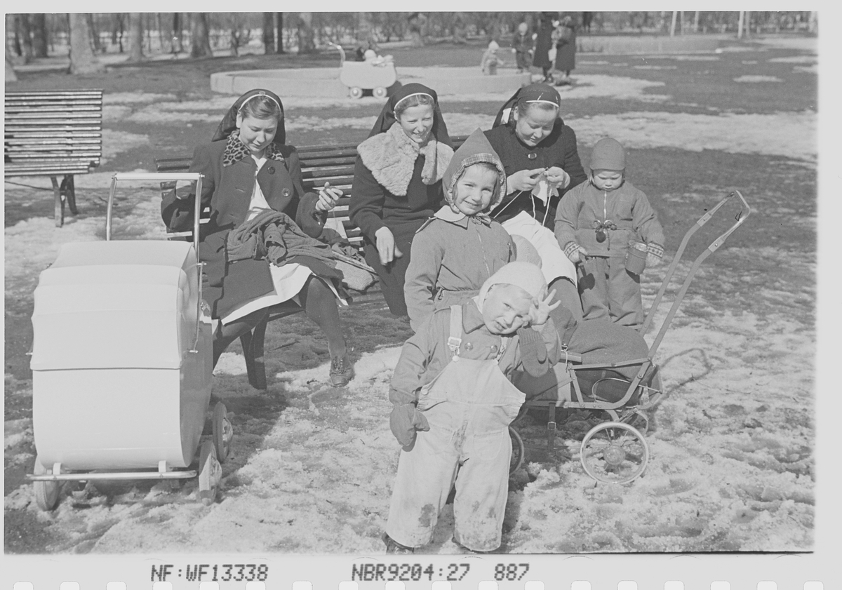 Antatt tre nonner passer barn i barnevogner på lekeplass. Fotografert 1940.