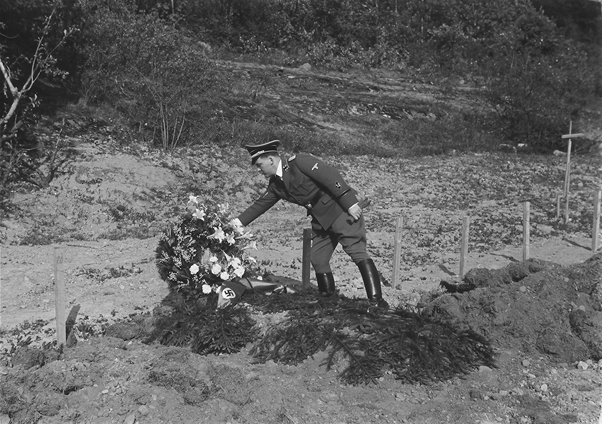 Mann i tysk naziuniform legger ned krans på nazigrav. Fotografert 1940.