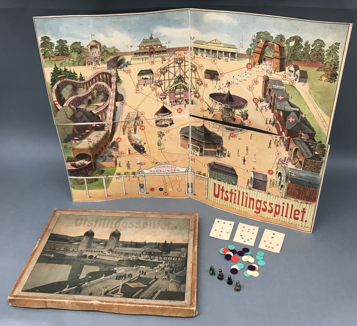 Brettspill med spillebrett som viser fornøyelsesavdelingen på Frognerutstillingen / Jubileumsutstillingen i 1914. Kort og brikker av papp, spillebrikker av metall.