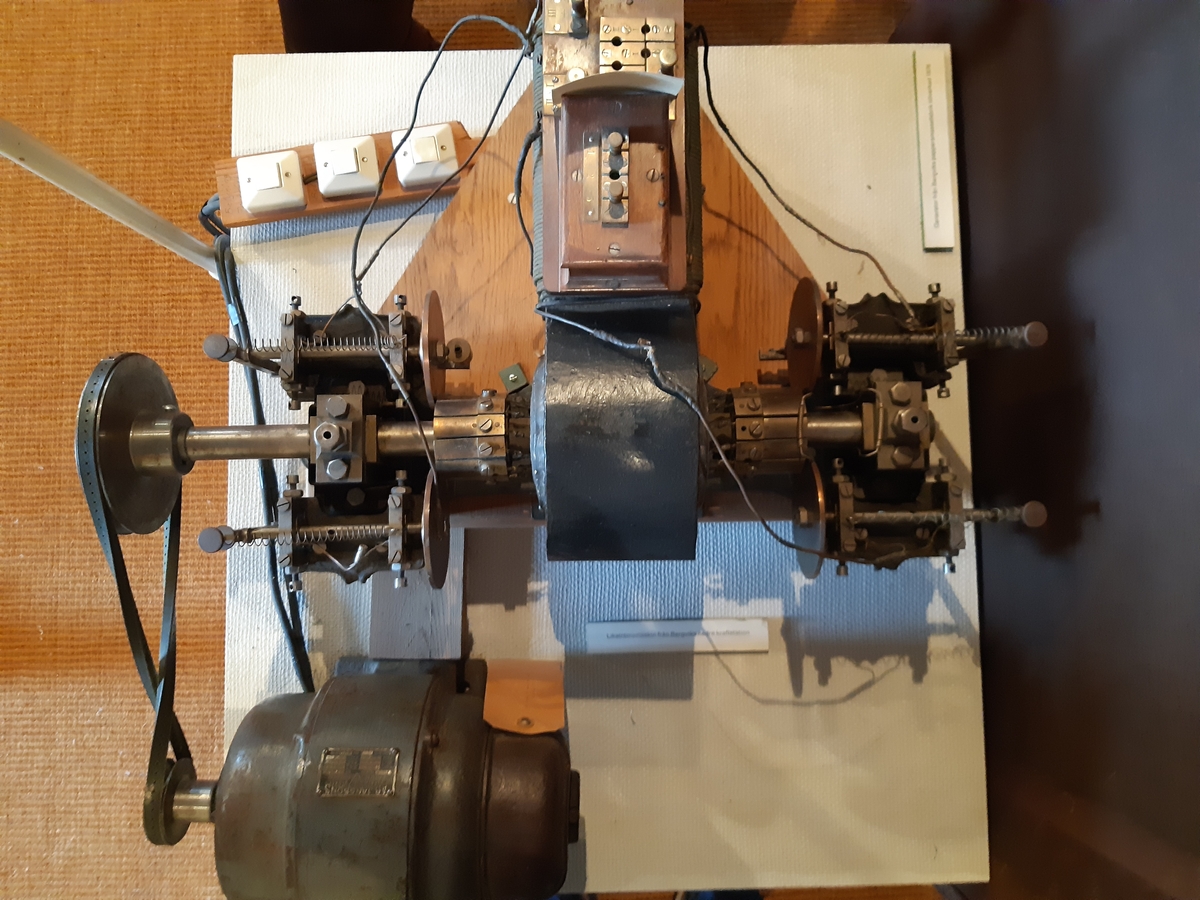 Troligen för galvanisering, provisoriskt fästad på en träplatta. Etsad skylt märkt: "Sigm. Schuckert/ Nürnberg/N:o 24". Fundamentet av gjutjärn, vilket är spräckt. En stoppmutter med refflad kant saknas och  åtta st. nitar fattas. (Motsvarande maskin i Deutsches Museum: 1.200 v/min 4 volt 30 amp.) 40 (?) volt 30 amp. 1200 varv.