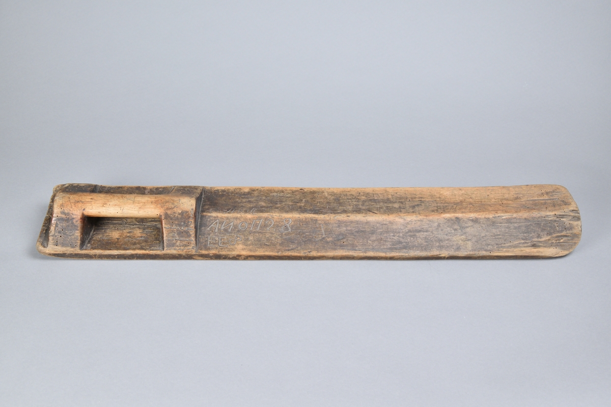 Kavelbräde tillverkat i trä, med rak och rektangulär form. Med handtag skuret från samma stycke. Ovansidan lätt profilerad med ett flertal inristningar, bland annat årtalet "1728". 