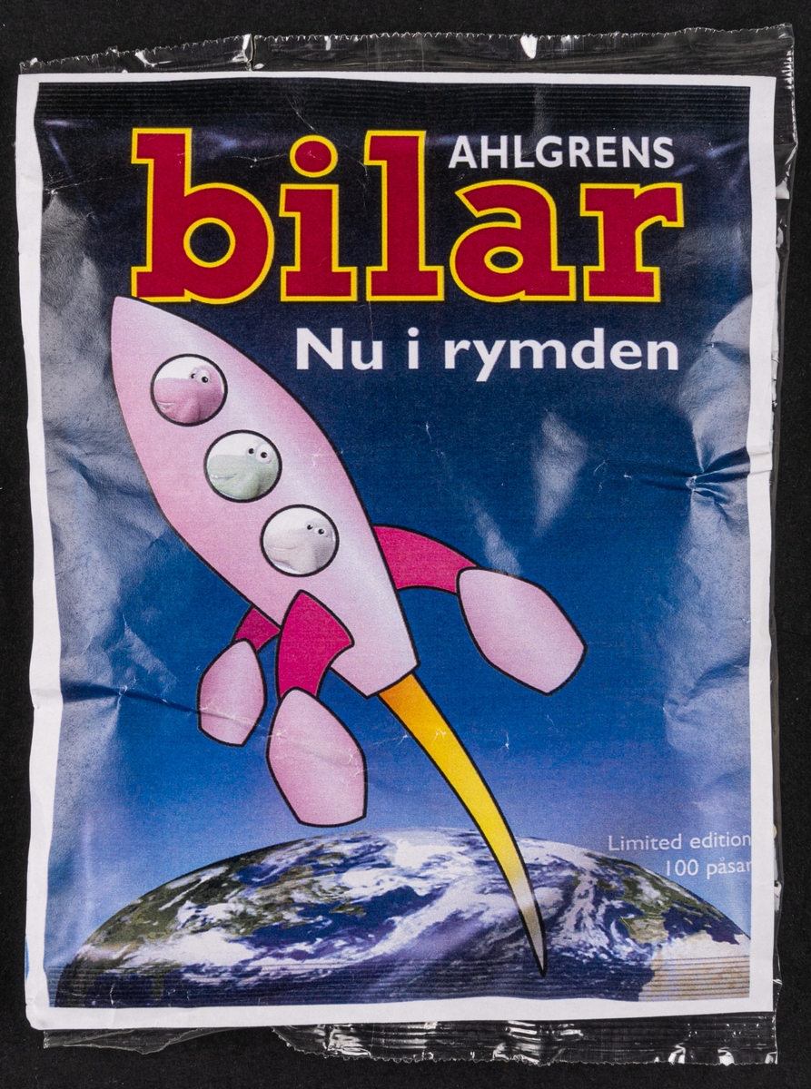 Godispåse i plast, innehållande Ahlgrens Bilar. Påklistrad pappersbild med text: "AHLGRENS bilar Nu i rymden".