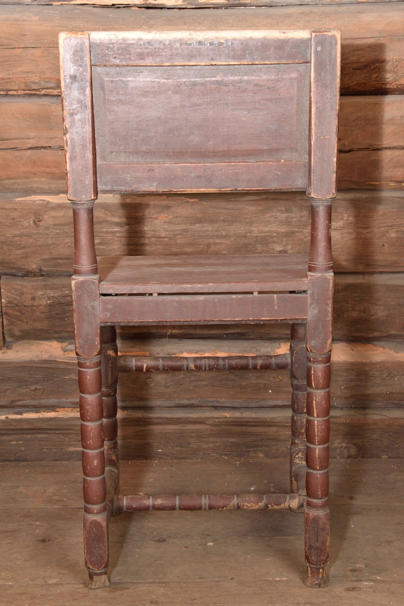 Stol tillverkad i furu, målad rödbrun. Med enkel rektangulär ryggbricka, delvis genombruten med rundade ryggstolpar. Enkel ostoppad sits. Stolen står på fyra profilsvarvade ben, med svarvad framslå samt svarvat H-format benkryss. Benen med konformade fotavslut. 
