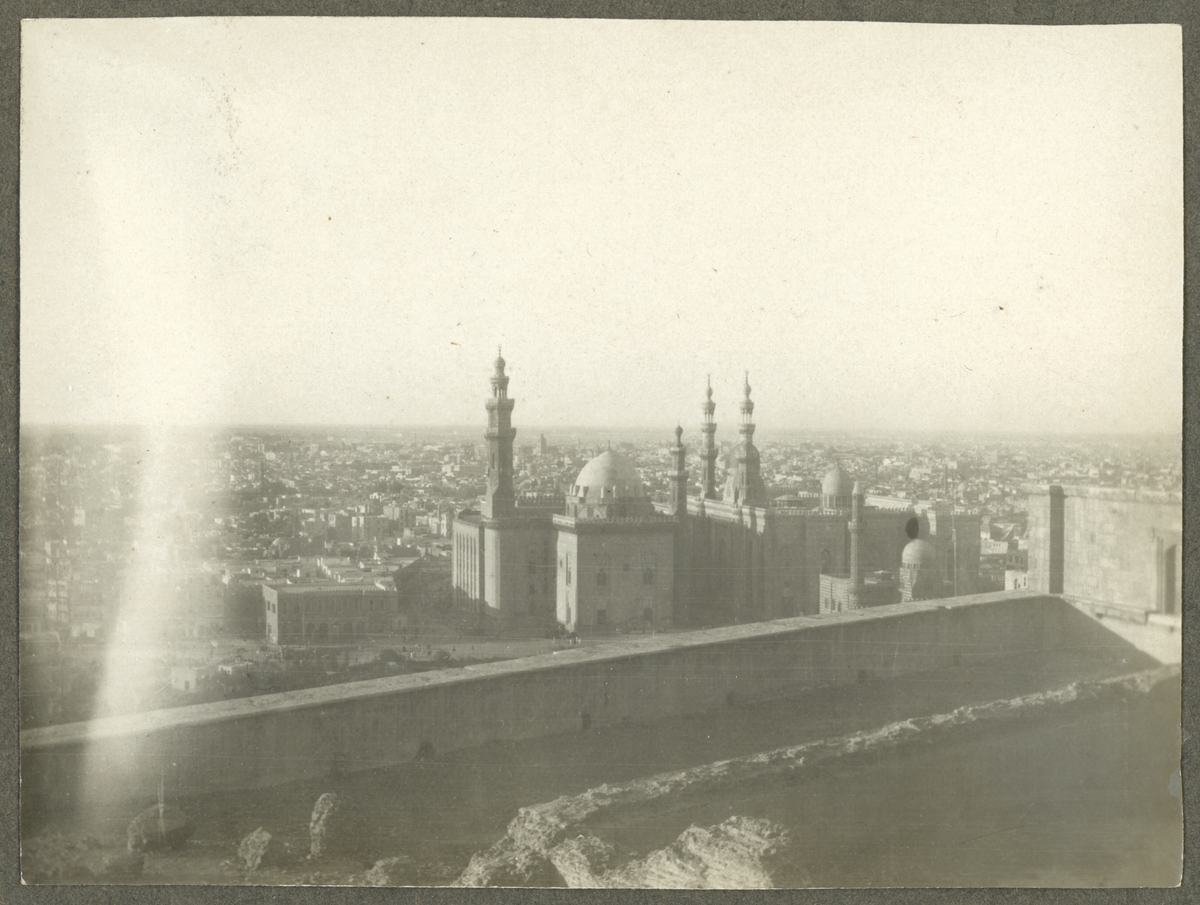 Bilden föreställer en stadsvy över Kairo från citadellen. I bildens centrum syns Sultan-Hasan moskén.