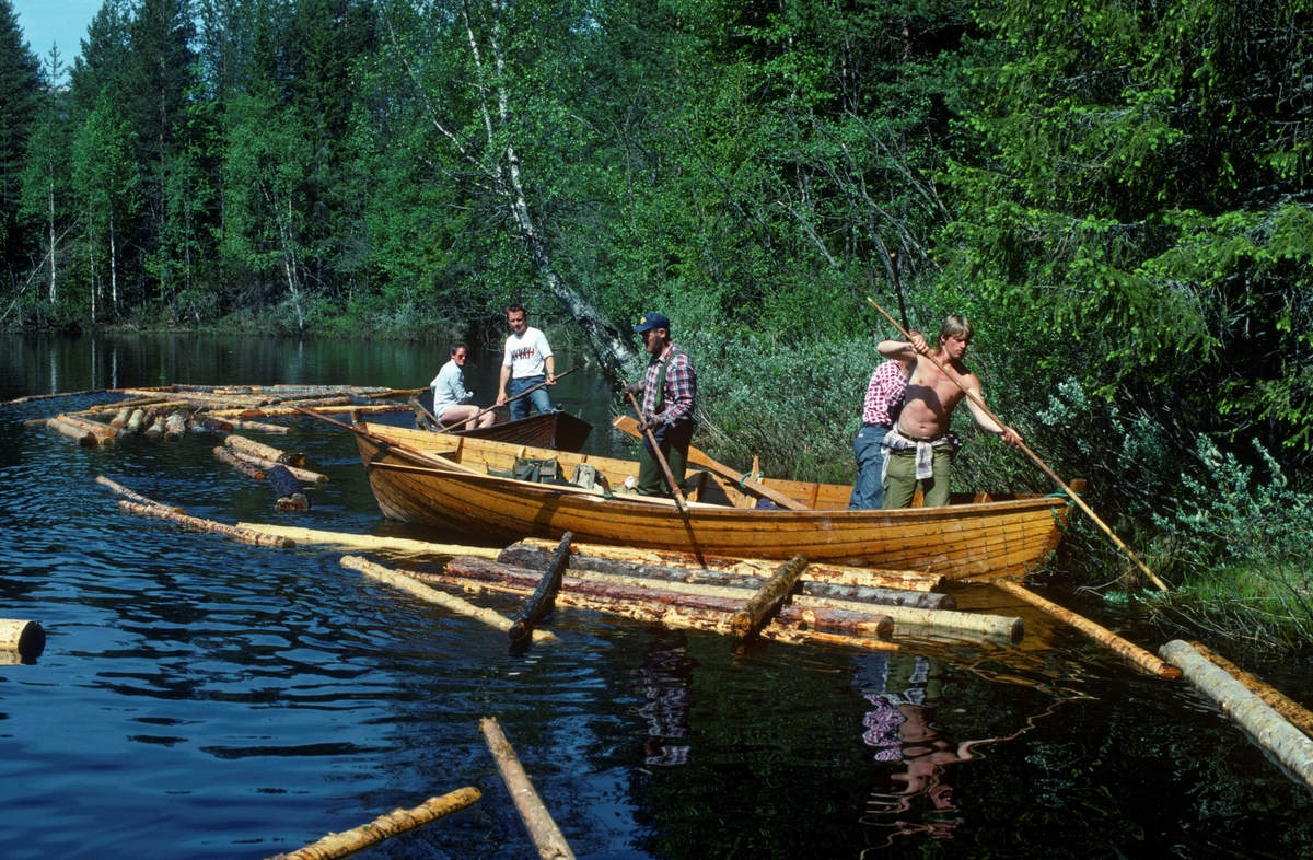Såkalt «landrensk» eller «sluttrensk» i Trysilelva, like nord for kommunesenteret Innbygda i 1989. Fotografiet er tatt i motstrøms retning på en forholdsvis stilleflytende elvestrekning. I forgrunnen ser vi en robåt med tre stående karer om bord. Båten gikk tett inntil en krattbevokst elvebredd, der fløterne hogg fløterhakene sine i stokker som hadde blitt liggende mot land og trakk dem utover i elveløpet igjen. Bak dem kom det en annen båt, som også gikk tett opp mot land. I den andre båten var det to menn, en som sto klar med fløterhaken og en som satt på aktertofta, der han antakelig manøvrerte en påhengsmotor. Bak den bakerste båten hang det antakelig ei lita lense, ei flytende lenke av sammenkjedete tømmerstokker, som skulle fange opp løstømmeret slik at fløterne kunne kjenne seg trygge på at alle stokkene fulgte med strømmen videre nedover elveløpet.