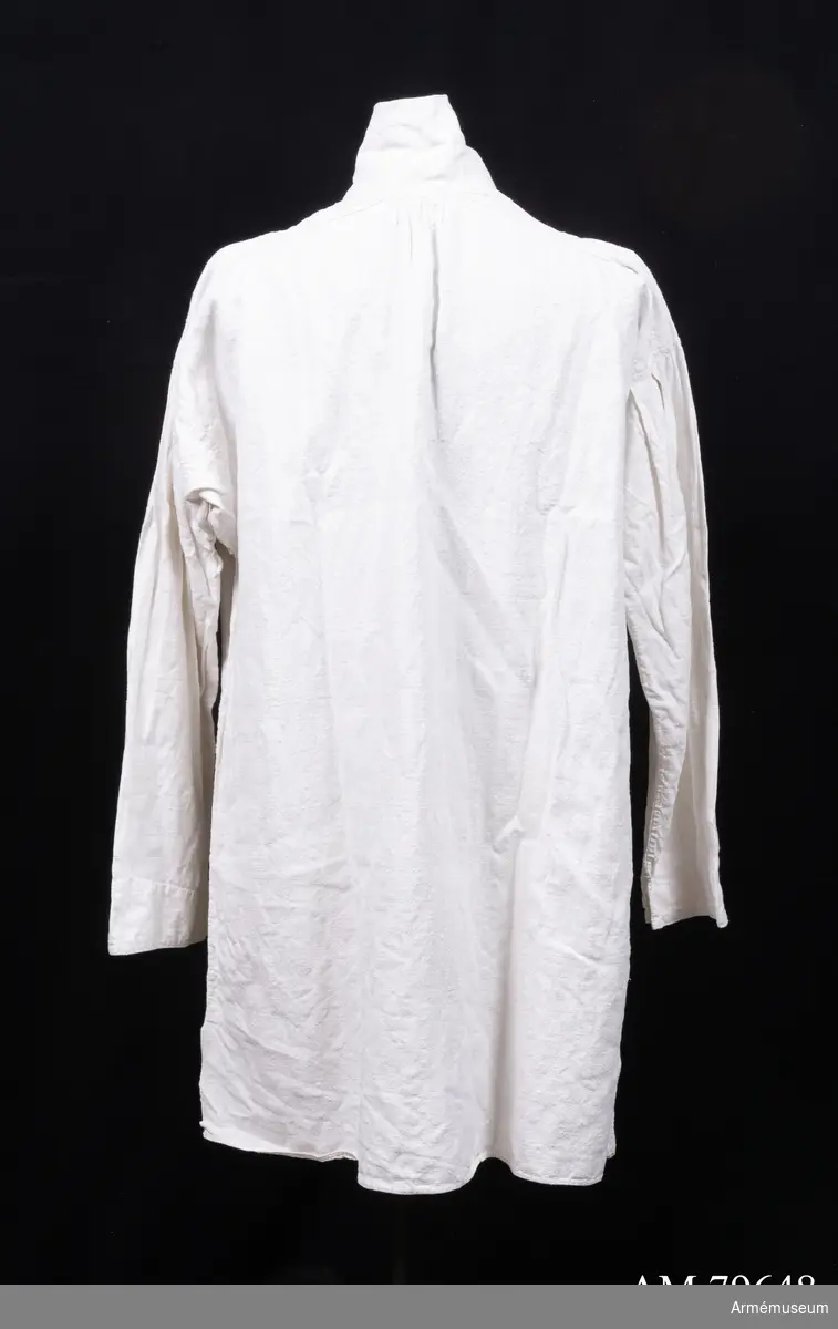 Skjorta av grov vit linnelärft med tre stämplar framtill: ”?813” (otydlig), ”År 1856” och ”Krigssjukvårdsförrådet T4”. Skjortan har långa ärmar med litet sprund nertill, ok på axlarna, hög ståndkrage med sydda snörhål för snodd i varje sida, djupt halssprund med träns, och slits i sidsömmarna nertill. Den är helt handsydd.
Tyget är handvävt i 640 mm bredd - stadkant syns i båda slitsarna nertill.

Troligen är plagget en skjorta m/1845, nattskjorta eller sjukhuströja. Jämför t ex AM.013574.