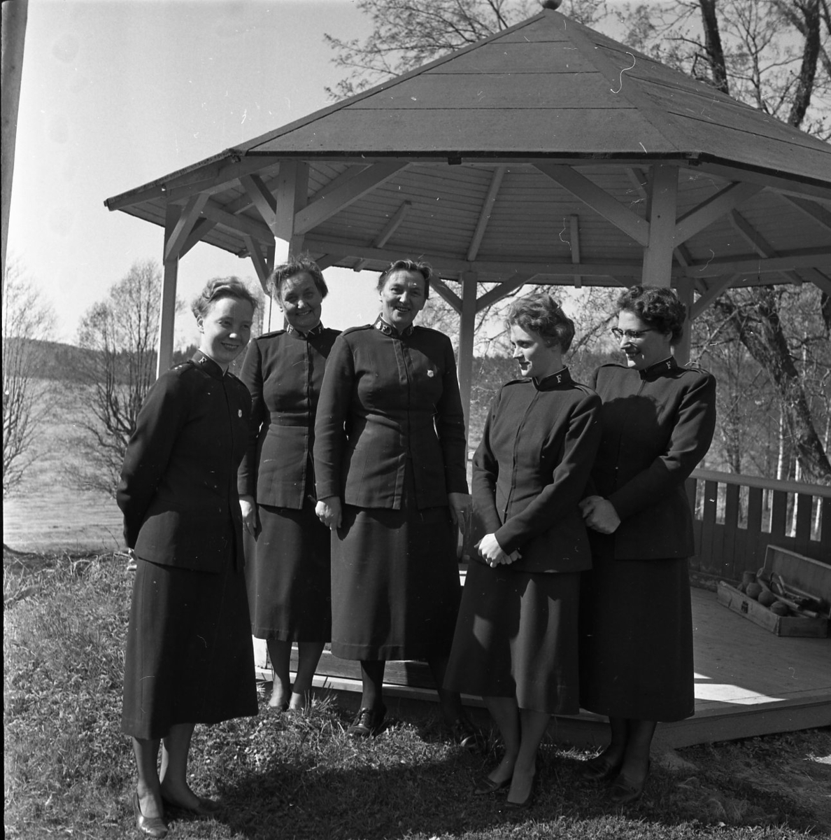 Fem kvinnor från frälsningarmén står uppställda för fotografering framför en paviljong.