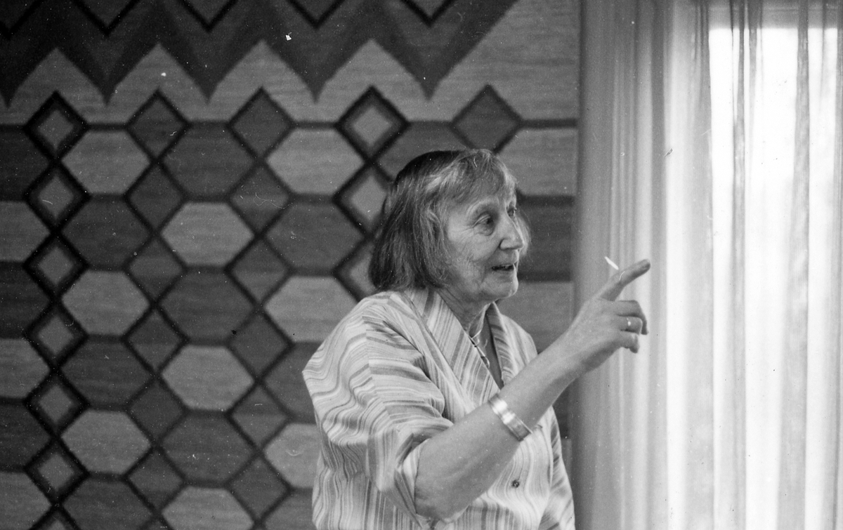 Knäreds sn. Vävateljén i Knäred, besök hos Judith och John Johansson den 15 maj 1985.
Motivtext 1-9: Judith Johansson i ateljéns visningsrum.