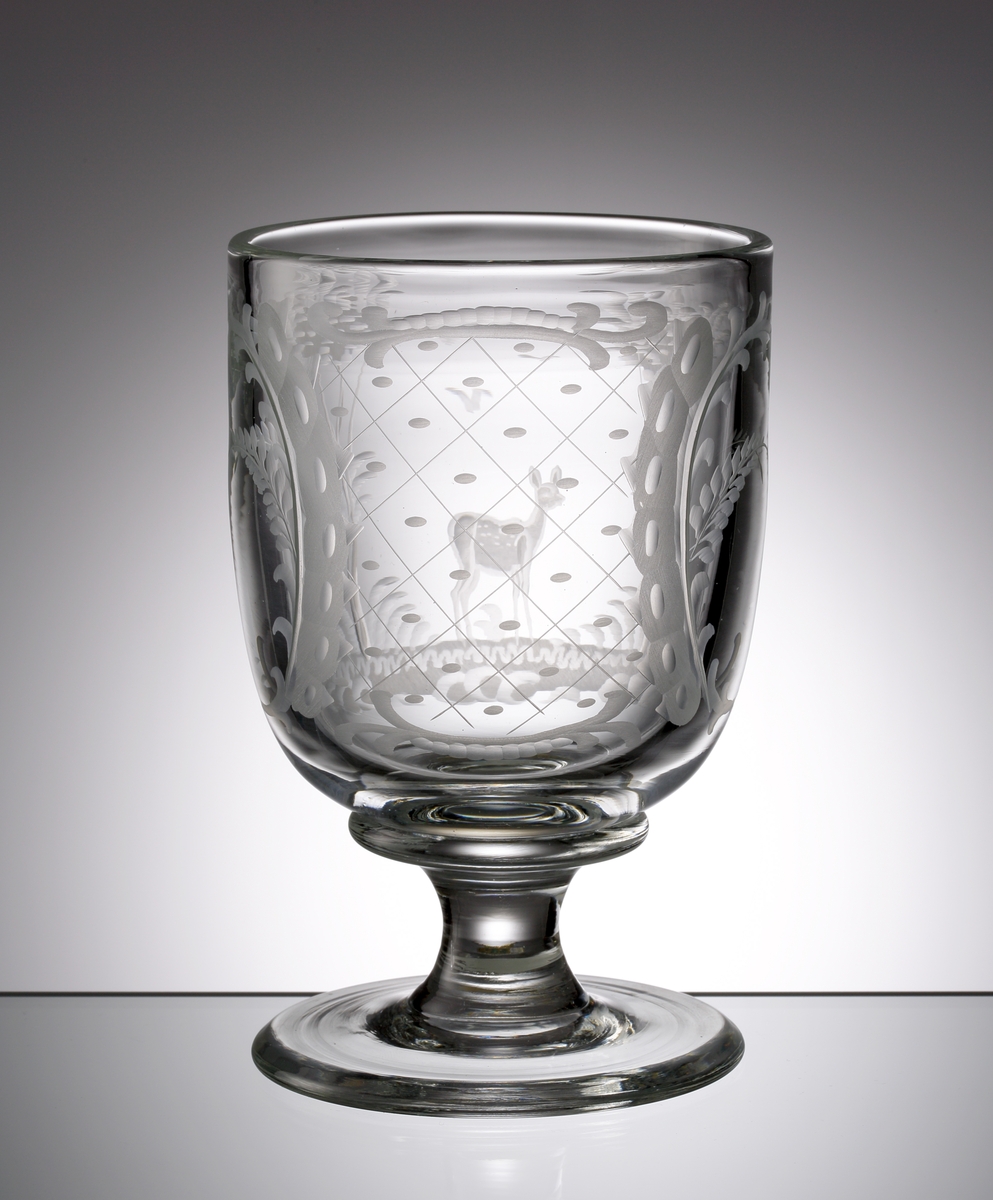 Inspiration från 1600-1700-talets tyska glas med graverade  jakt- och naturscenerier. Guldfärgad etikett med grönblå text "REIJMYRE 1810 KRISTALL SWEDEN"