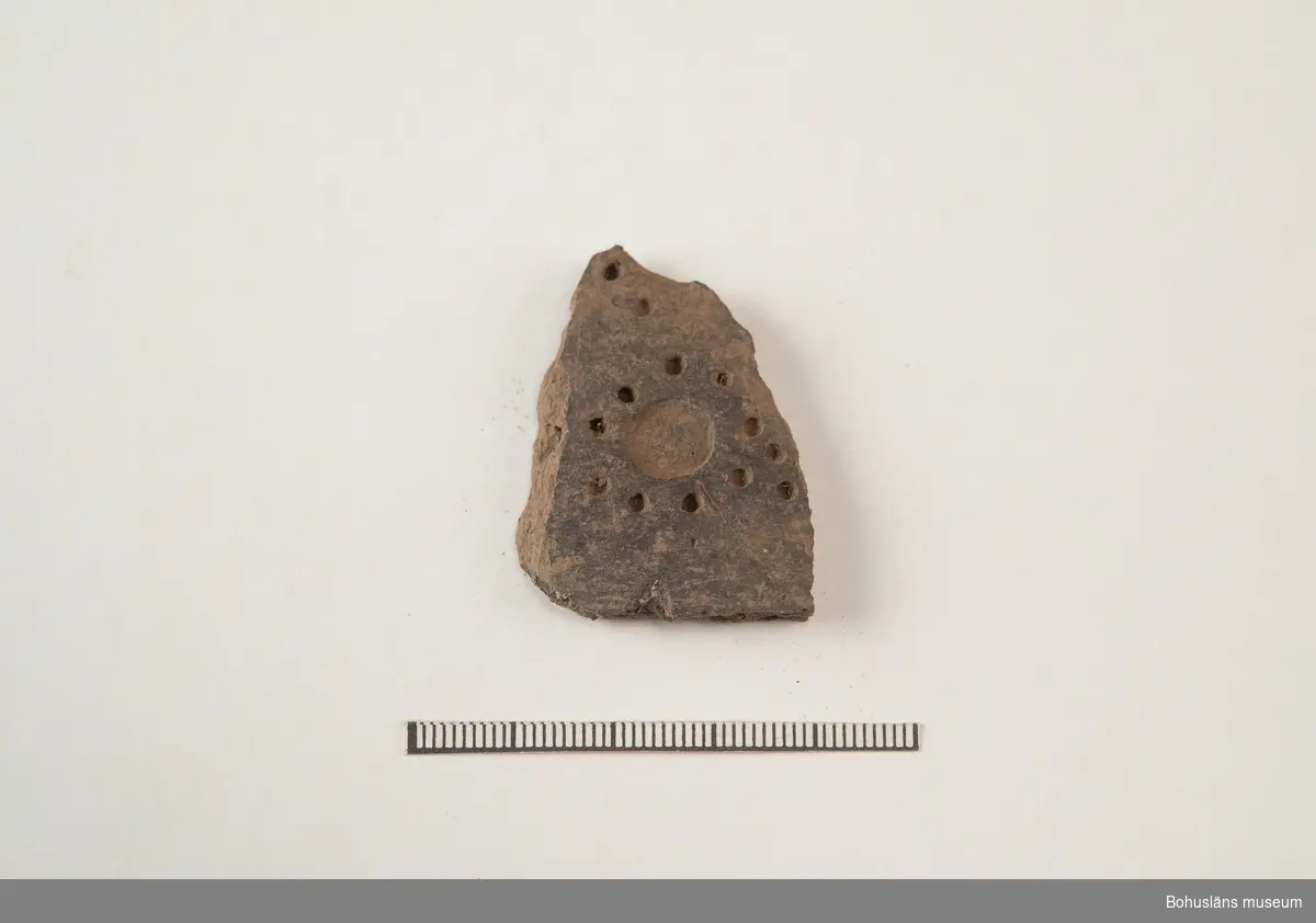 Kärl, svartglättat fragment med stämpel-/punktdekor. Rosettmönster? Se kärlfragment fnr. 28E

294 Landskap BOHUSLÄN