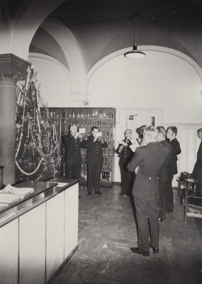 Et lite politiorkester spiller ved et pyntet juletre ved resepsjonen på hovedpolitistasjonen i Møllegaten 19.