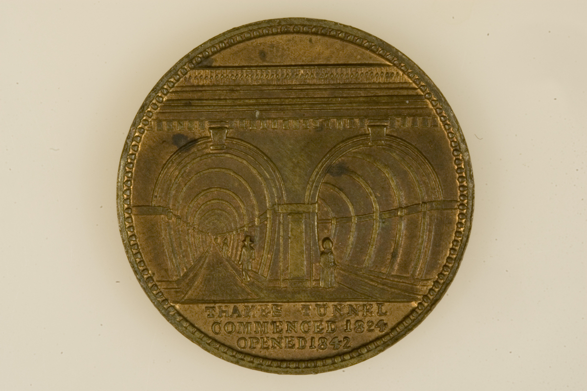 Motiv advers: Sir Isambart Marc Brunel i profil mot venstre. Medaljongen omgitt av laurbærgrener.

Motiv revers: Tunellen under Themsen.