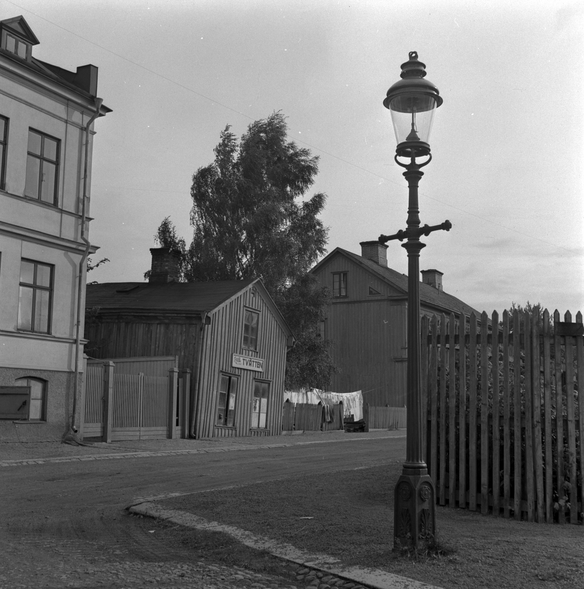 Gatukorsning i Jönköping. Längs vägen ligger sten- och trähus samt "June Tvätten" där tvätt hänger på tork.