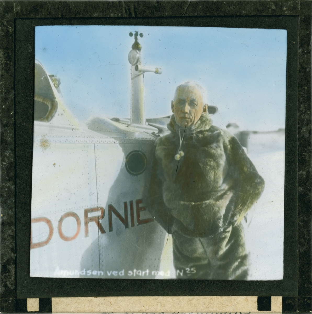 Håndkolorert dias. Roald Amundsen ved sjøflyet N-25, (Dornier Wal), før ferden til Nordpolen, 1925.