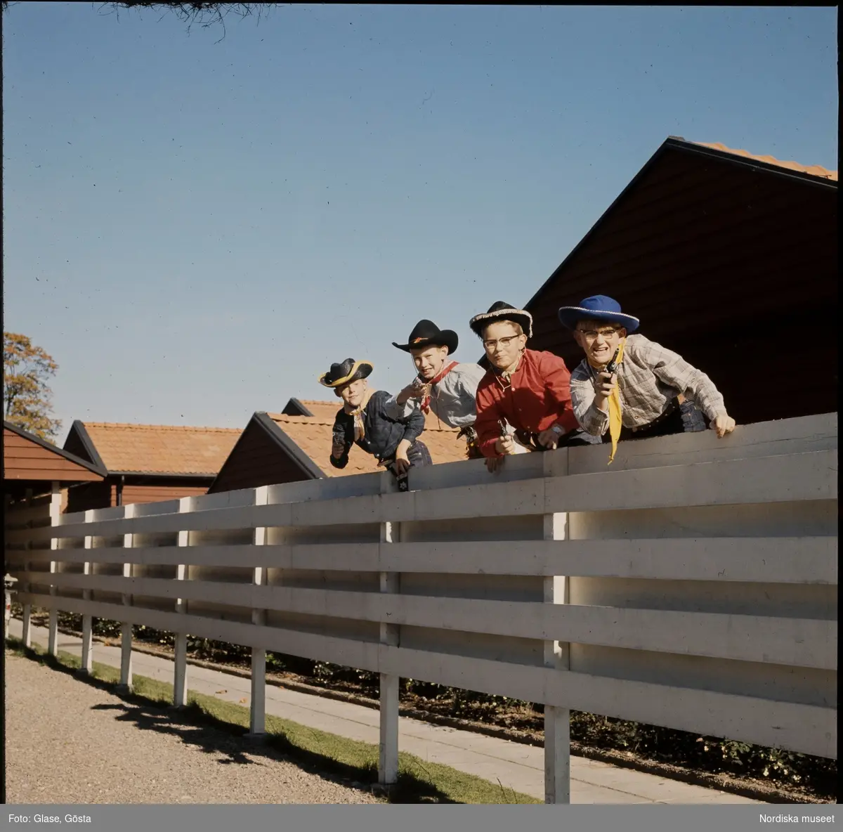 Fyra pojkar utklädda till cowboys leker i ett bostadsområde.