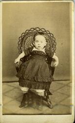 Portrett av ukjent barn,jente,  i kurvstol.