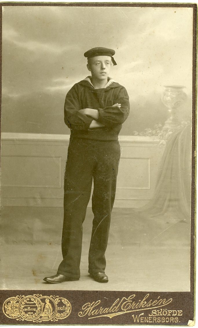Kabinettsfotografi av en ung man i flottans uniform. Han står med armarna i kors.