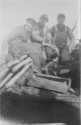 Tre fiskere sittende på fordekket på M/K "Bauta" fra Grovfjo