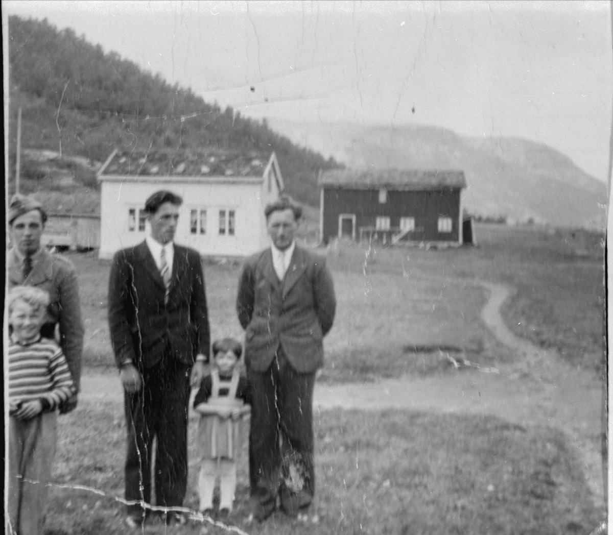 Gruppebilde av tre menn og to unger foran en gård på Myklevoll.