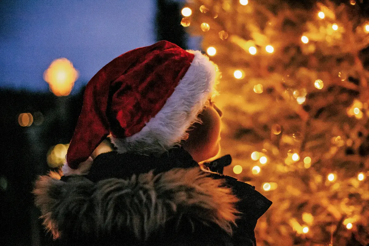 Barn med nisselue kikker på juletreet på Linderud gård.