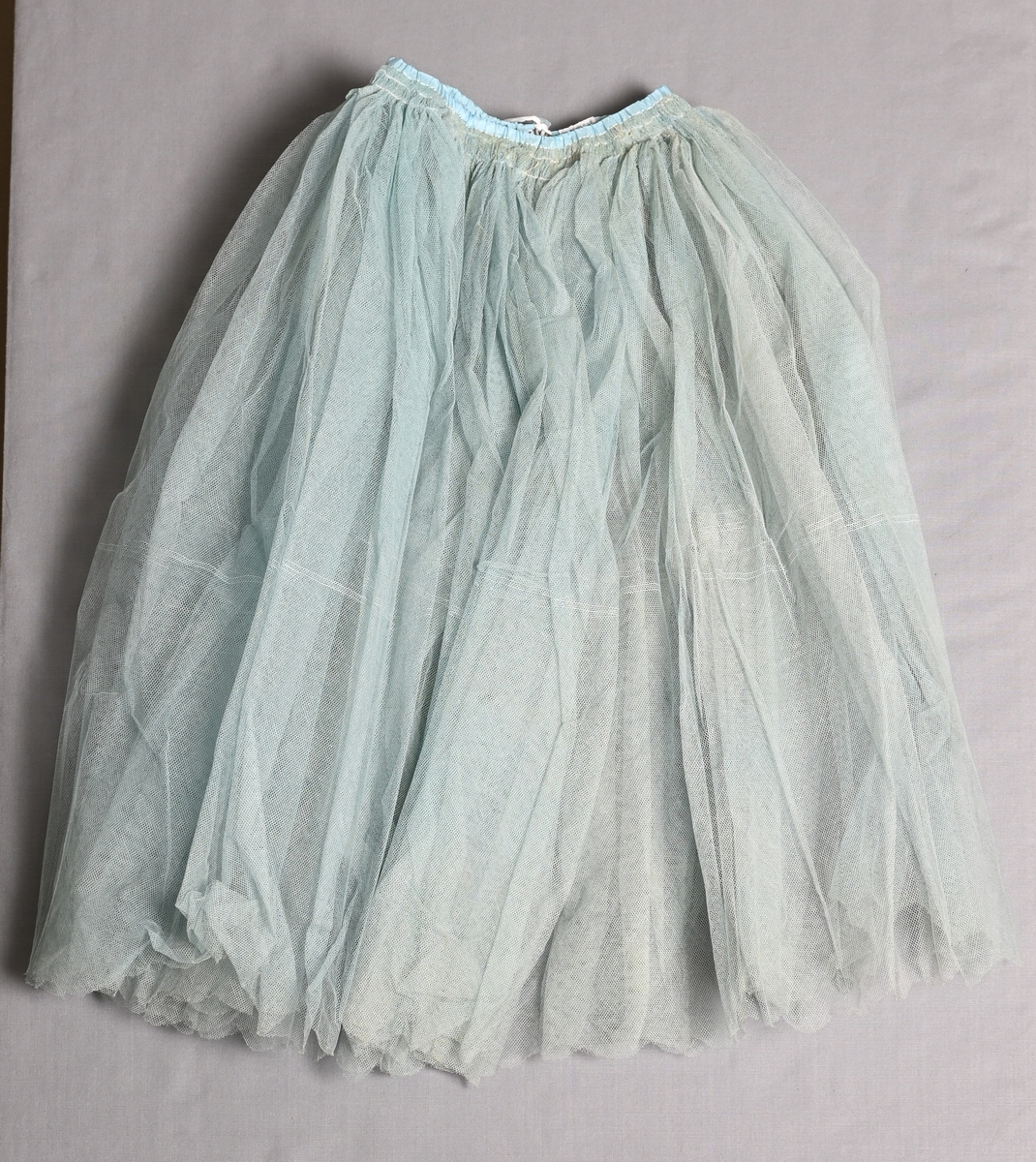 Mycket vid kjol av ljusblå bomullstyll. Knäpps med hyskor och hakar.