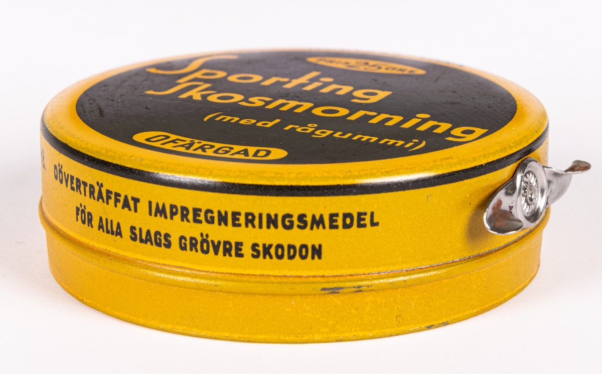 Plåtburk för skokräm, gul och svart med tryck text: "Sporting Skosmorning (med rågummi)". Tryckt bruksanvisning på sidan.