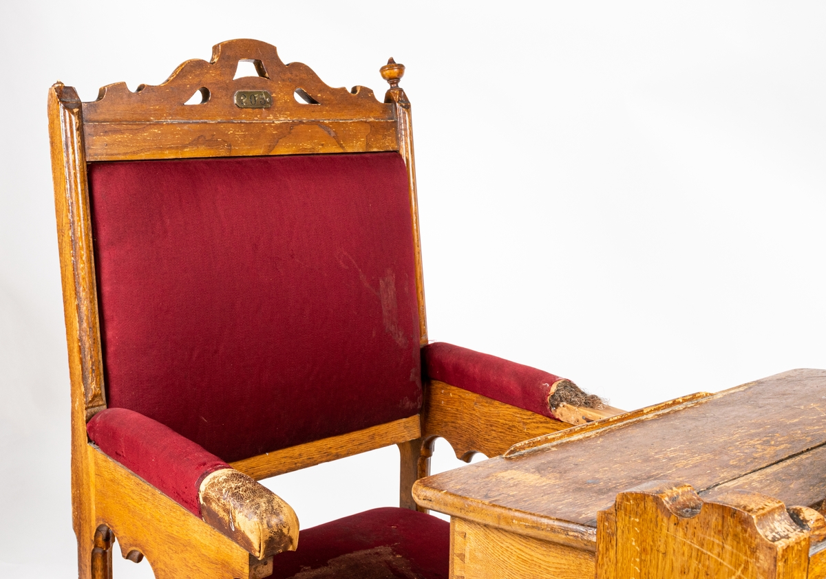 Riksdagsstol bestående av pulpet med tillhörande stol. Röd klädsel.