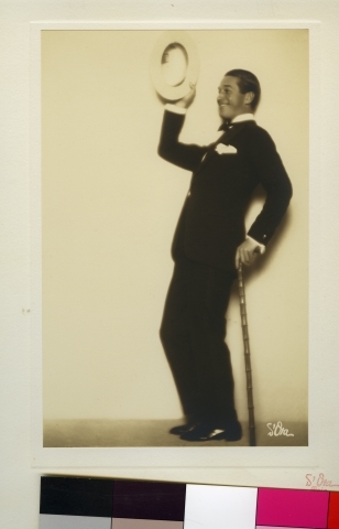 Maurice Chevalier i dress med hatt og stokk.