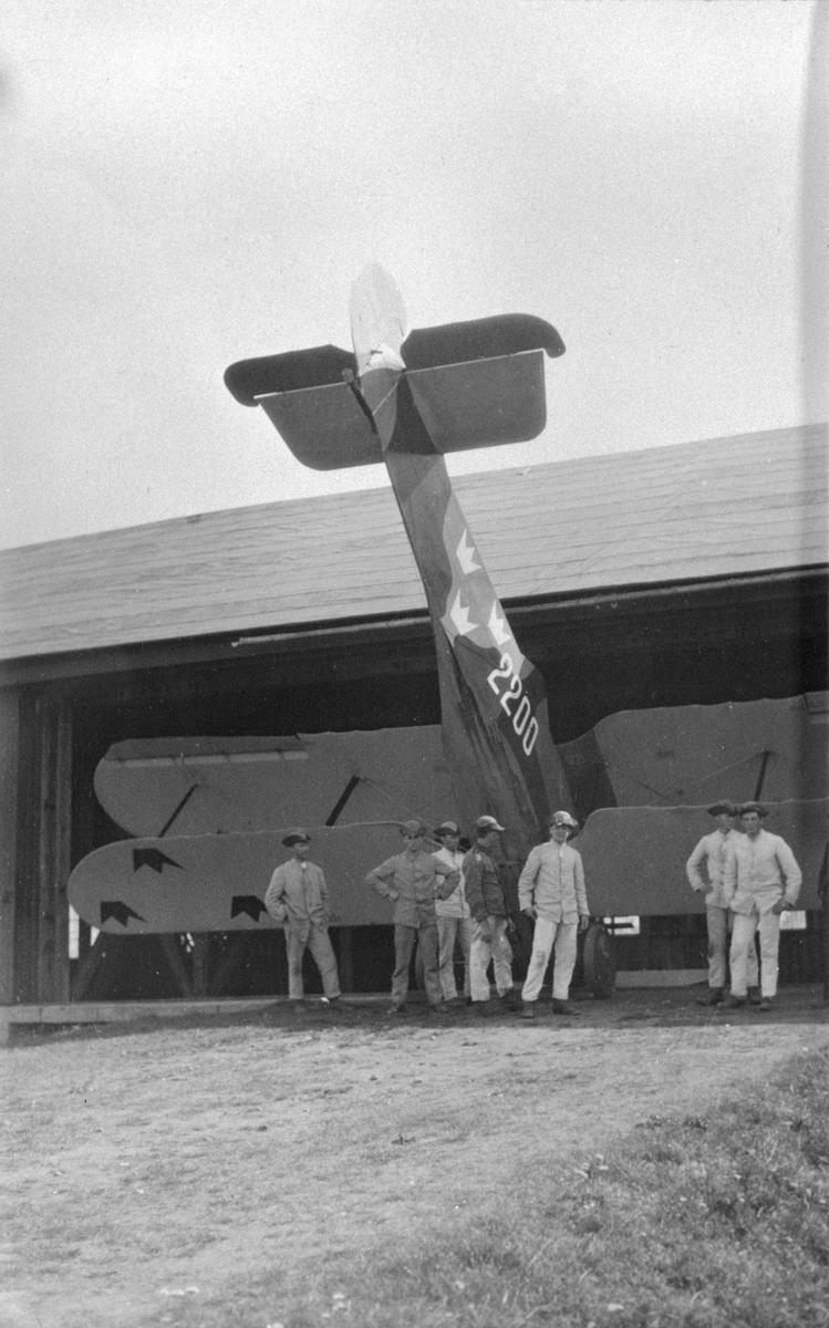 Prototypen till flygplan FVM S 21, nr 2200 står på nosen vid F-hangaren på Malmen. Sju militärer vid planet. Omkring 1923-1926.