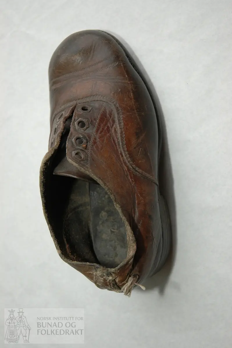 Sko. Låg sko med pløse på innsida og maljer til knyting. Lærsolar. 3 stk jernpluggar til beslag under.