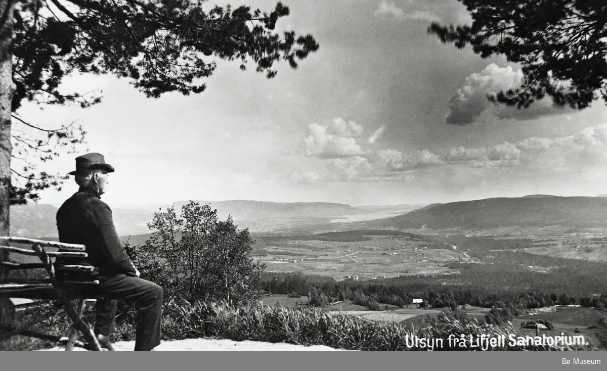 Mann på Lifjell sanatorium sit på benk og ser ut over Bø-bygda.