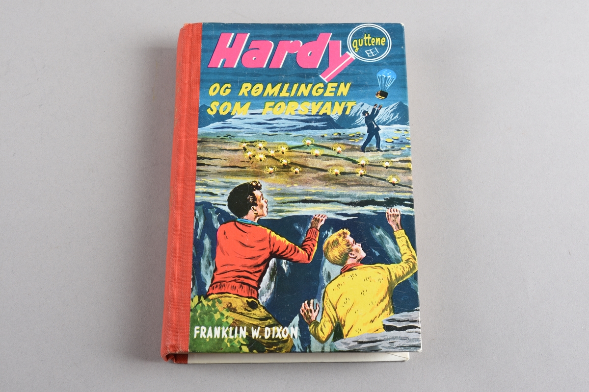 Barnebok nr. 40 i serien om "Hardy-guttene". Boka har shirting i ryggen. Stive permar trekt med papir med fleirfarga motiv på framsida, tekst på baksida. Gullfarga trykk på ryggen. 142 sider.