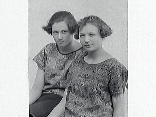 Ateljéporträtt av två unga kvinnor i modernt korta frisyrer och mönstrade blusar. Lissie Hjalmarsson beställde bilderna och är troligen en av kvinnorna.