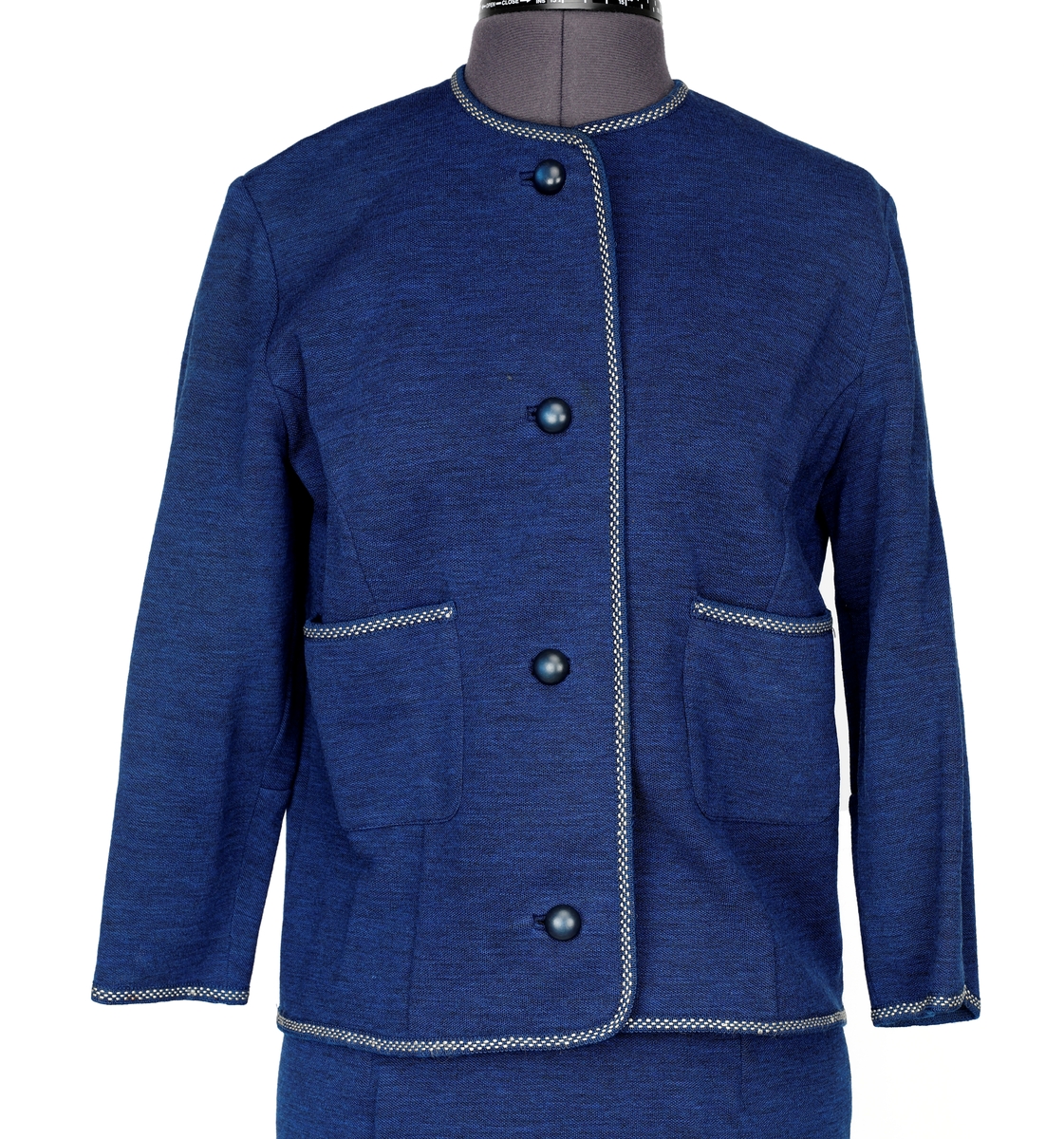 Drakt kjole (jakke og skjørt), fra Canada. 
Jakke: Bånd rundt det hele, på begge sider (holder formen). 4 knapper, 2 lommer sydd på.