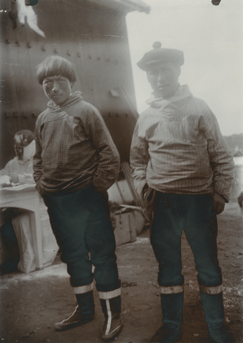 Fotografi från expedition till Grönland. Två män iklädda rutiga huvjackor poserar på en kaj.