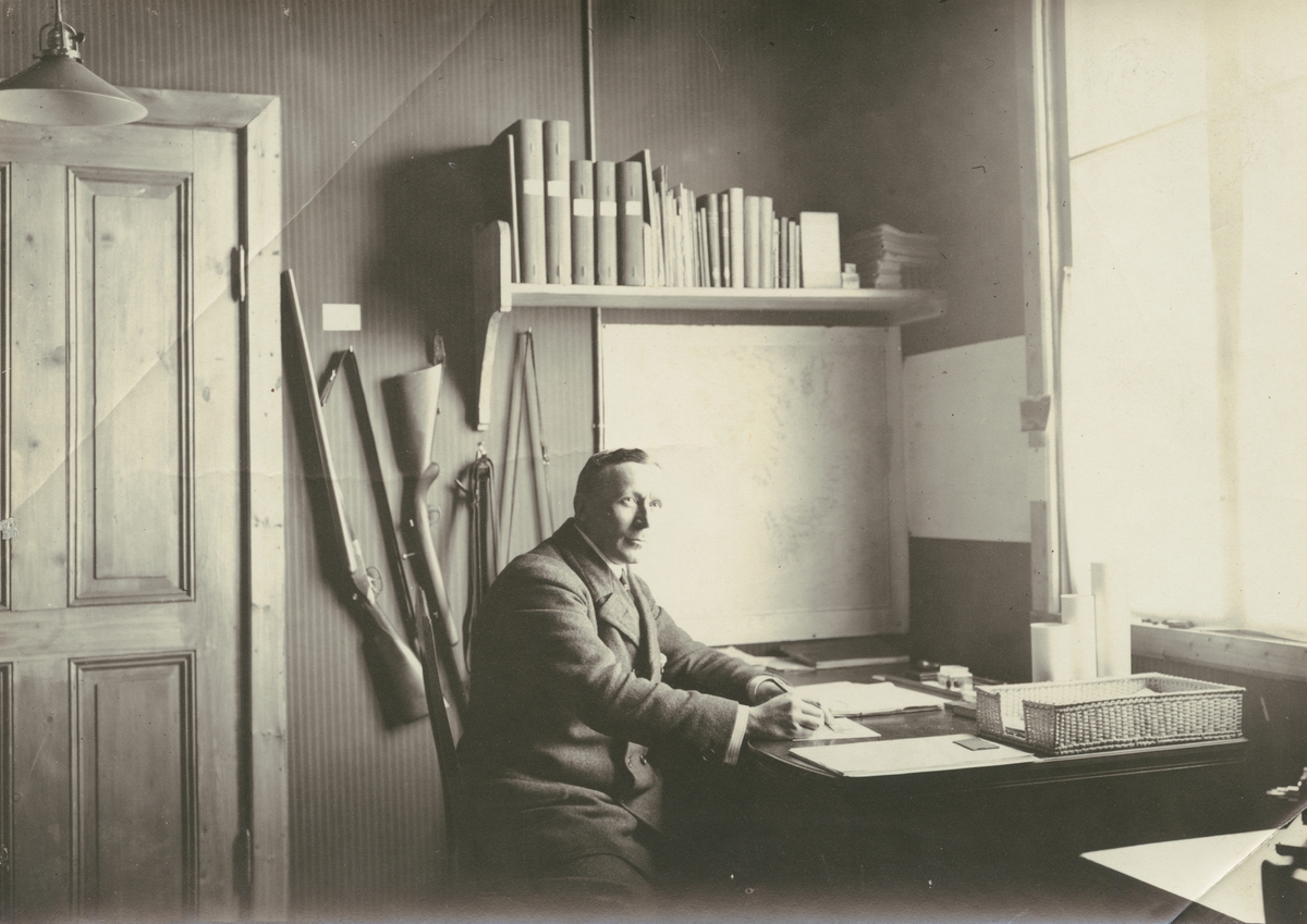 Fotografi från expedition till Spetsbergen 1920. Motiv av man som sitter och skriver vid ett skrivbord.