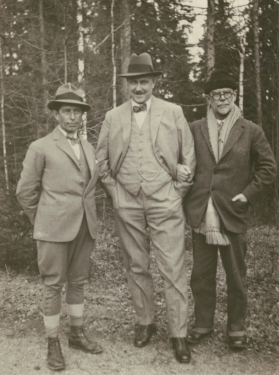 Diverse bilder från Fred Goldbergs samling. Motiv av tre män som poserar framför träd. Mannen till vänster är Knud Rasmussen. Bilden är tagen 1/5 1927.