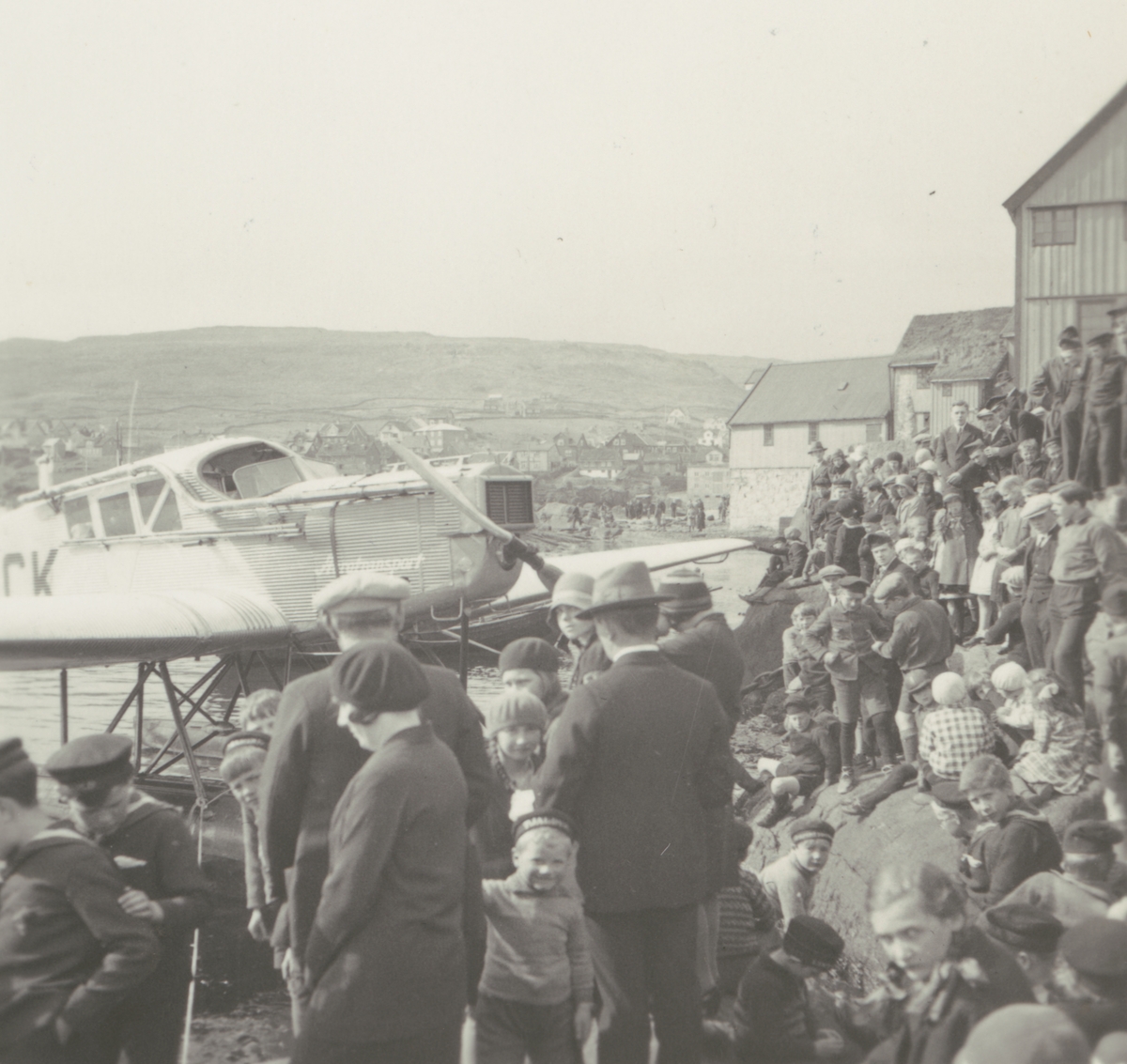 Fotografi från Albin Ahrenbergs resa till Grönland 1929. Motiv av en stor samling människor vid flygbåt i stad.